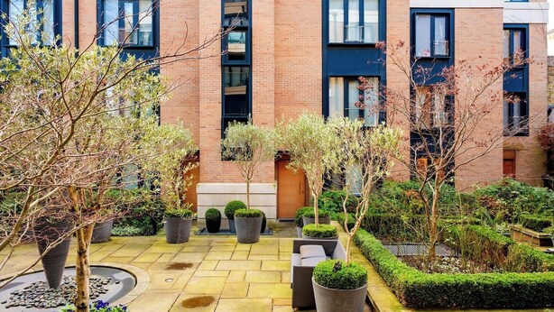 A modern building with a courtyard featuring potted plants and a seating area. - Deluxe and Peace in Primrose Hill (Greater London)
