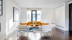 A modern living room with a sofa set, two armchairs, a vase with flowers, and a large window. - Deluxe and Peace in Primrose Hill (Greater London)