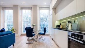 A modern kitchen with a built-in oven and a dining area with a glass table and blue chairs.