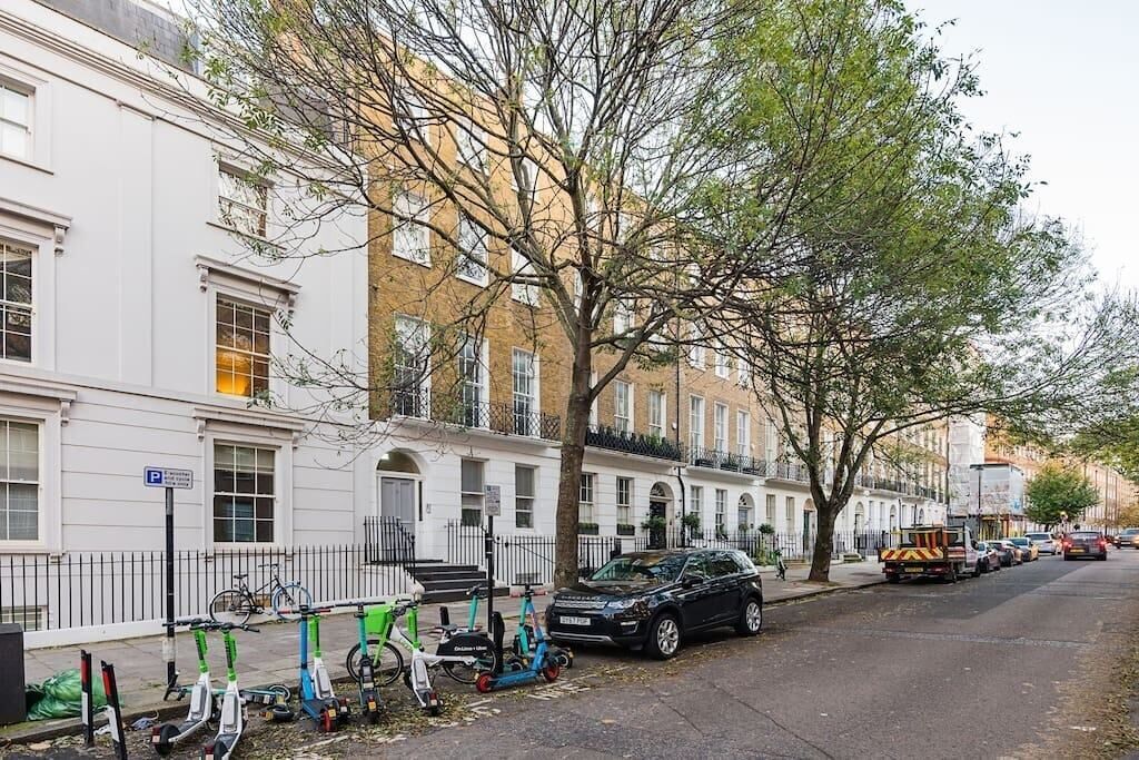A row of white townhouses with a tree in the foreground.