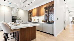 A modern kitchen with a central island, bar stools, and a built-in wine rack. - West end Deluxe flat N.2 (Greater London)