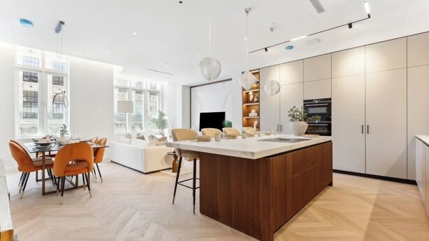A modern kitchen with a central island, wooden cabinets, and a dining area with orange chairs. - West end Deluxe flat N.2 (Greater London)