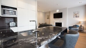A modern kitchen with a marble countertop, stainless steel appliances, and a built-in oven.