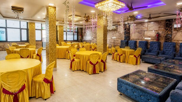 Un salón de banquetes con mesas redondas, sillas amarillas y sofás azules.