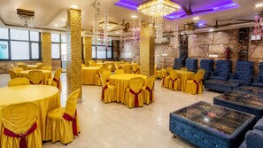 A banquet hall with round tables, yellow chairs, and blue sofas. - HOTEL VISHAL PALACE  (Unnao)