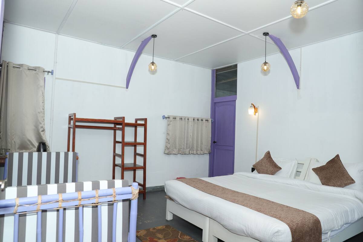 A bedroom with a bed, a wooden ladder, a striped chair, and a window with curtains.