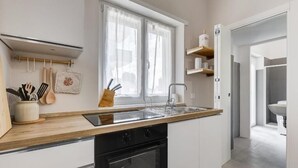 Eine moderne Küche mit Holzarbeitsplatte, schwarzen Geräten und einem Fenster mit durchsichtigen Vorhängen.
