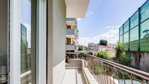 Ein Balkon mit Metallgeländer, Blick auf benachbarte Gebäude und ein klarer Himmel.