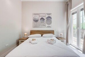 A hotel room with a large bed, two bedside tables with lamps, a wall art piece, and a window with curtains. - Eco Domus Moon (Roma)