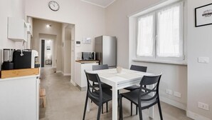 Une cuisine moderne avec un coin repas, un réfrigérateur, un four à micro-ondes et une horloge murale.