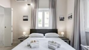 Une chambre d’hôtel avec un grand lit, deux tables de chevet, une fenêtre avec des rideaux et une porte.