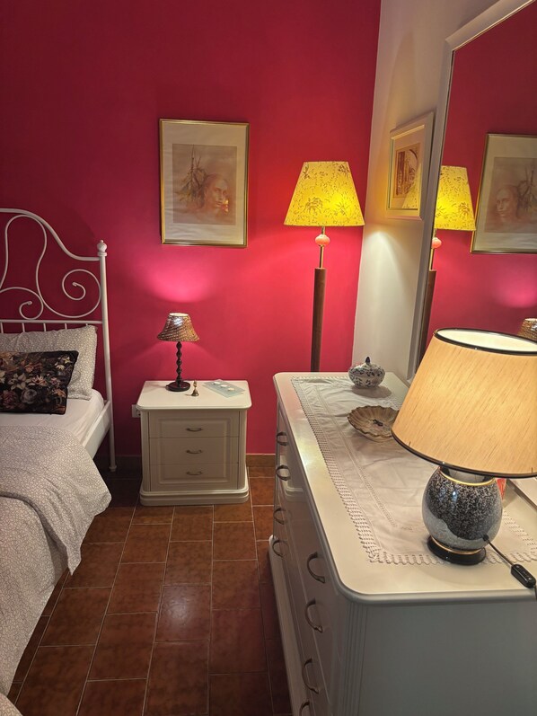 A bedroom with a bed, nightstand, dresser, and a mirror.
