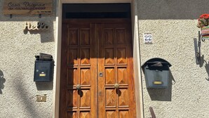 Eine hölzerne Doppeltür mit Schlüsselloch, einem Briefkasten und einem Schild darüber.