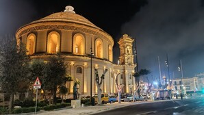A historic building with a dome and bell tower, surrounded by trees and street signs. - Charming Maltese townhouse (Il-Mosta)