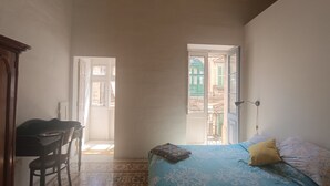 A bedroom with a bed, a chair, and a desk. There are two doors leading to outside areas. - Charming Maltese townhouse (Il-Mosta)