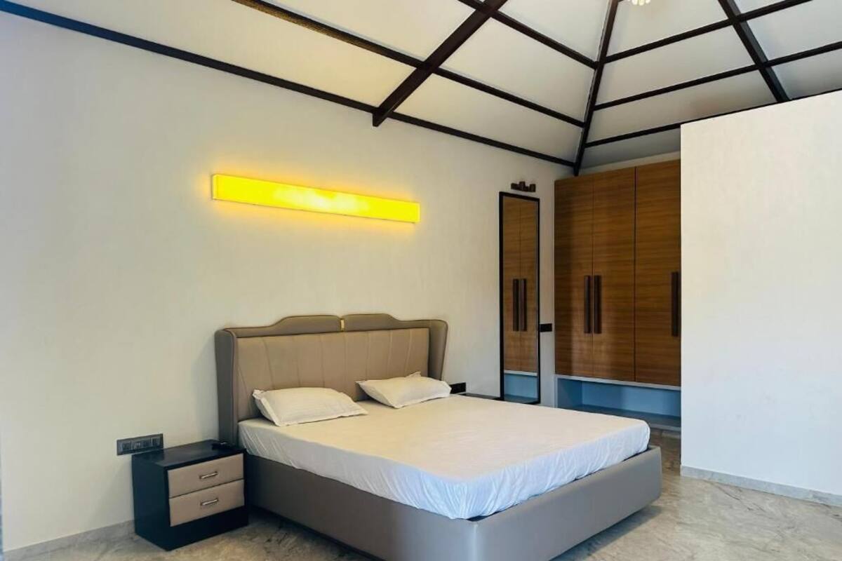 A modern bedroom with a bed, bedside tables, a nightstand, and a built-in wardrobe.