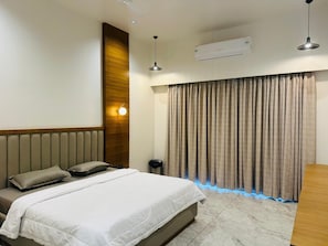 A bedroom with a bed, a wall-mounted air conditioner, a ceiling light, and a curtain with a blue light strip.