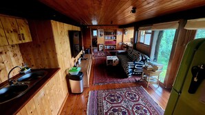 Een houten cabin met keuken, eethoek en woonkamer.