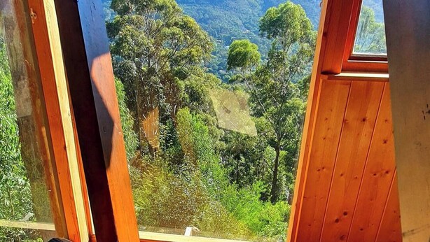 Een kamer met houten kozijnen en uitzicht op een bergachtig landschap.