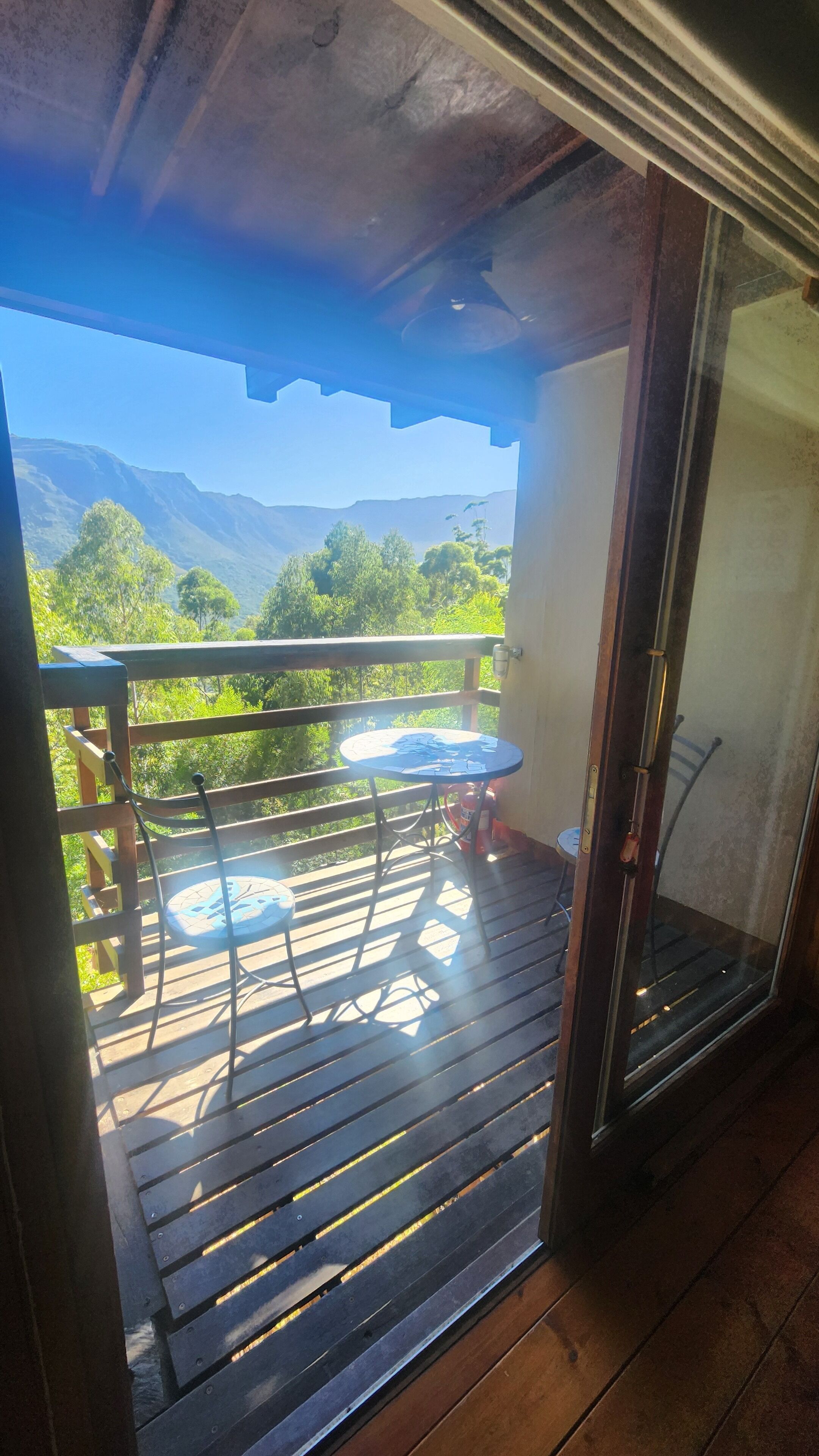 Un balcón con mesa y sillas, con vista a un paisaje montañoso.
