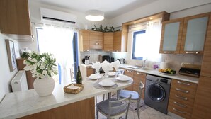 Een moderne keuken met houten kasten, een ingebouwde wasmachine en een eethoek met een witte vaas en een gedekte tafel.
