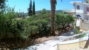 Un quartier résidentiel avec un mur en pierre, un palmier et un balcon doté d’une balustrade.