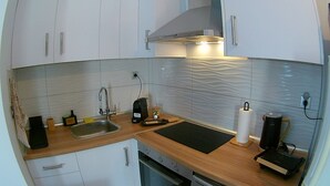 Une cuisine de taille réduite, équipée d’un évier, d’un plan de travail et d’une machine à café.