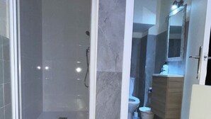 A modern bathroom with a glass-enclosed shower, a toilet, and a vanity with a mirror. - Studio with independent entrance in Madrid (Madrid)