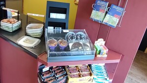 Une vitrine de boulangerie présentant diverses pâtisseries et une pancarte indiquant la proximité d’un parc de camping.