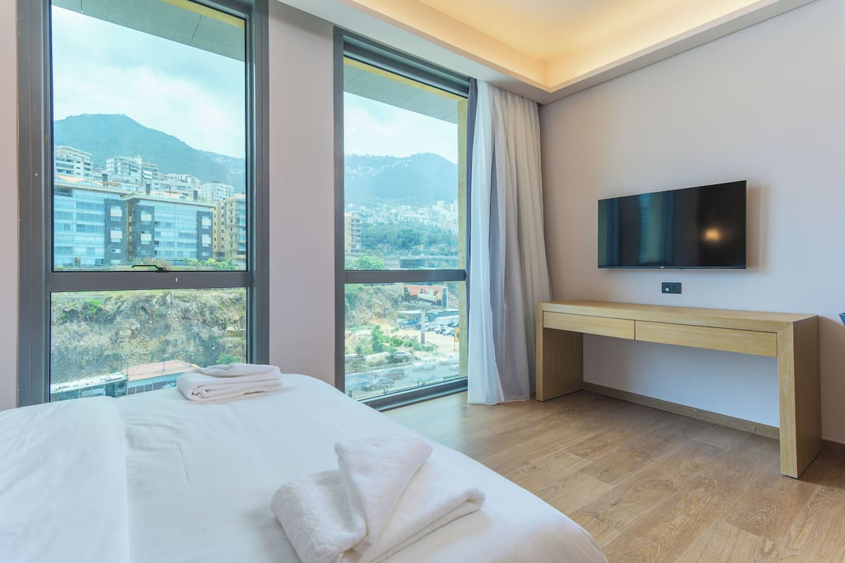 A hotel room with a large bed, a desk, and a TV.