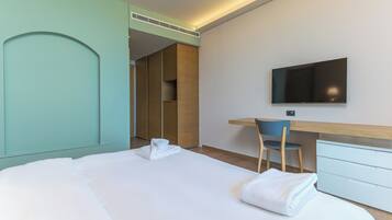 Een hotelkamer met een bed, bureau, stoel, televisie en een kledingkast.
