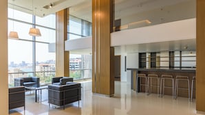 A modern interior with a seating area, a bar, and large windows offering a city view. - Jounieh Living - Residences by Local Host (Jounieh)