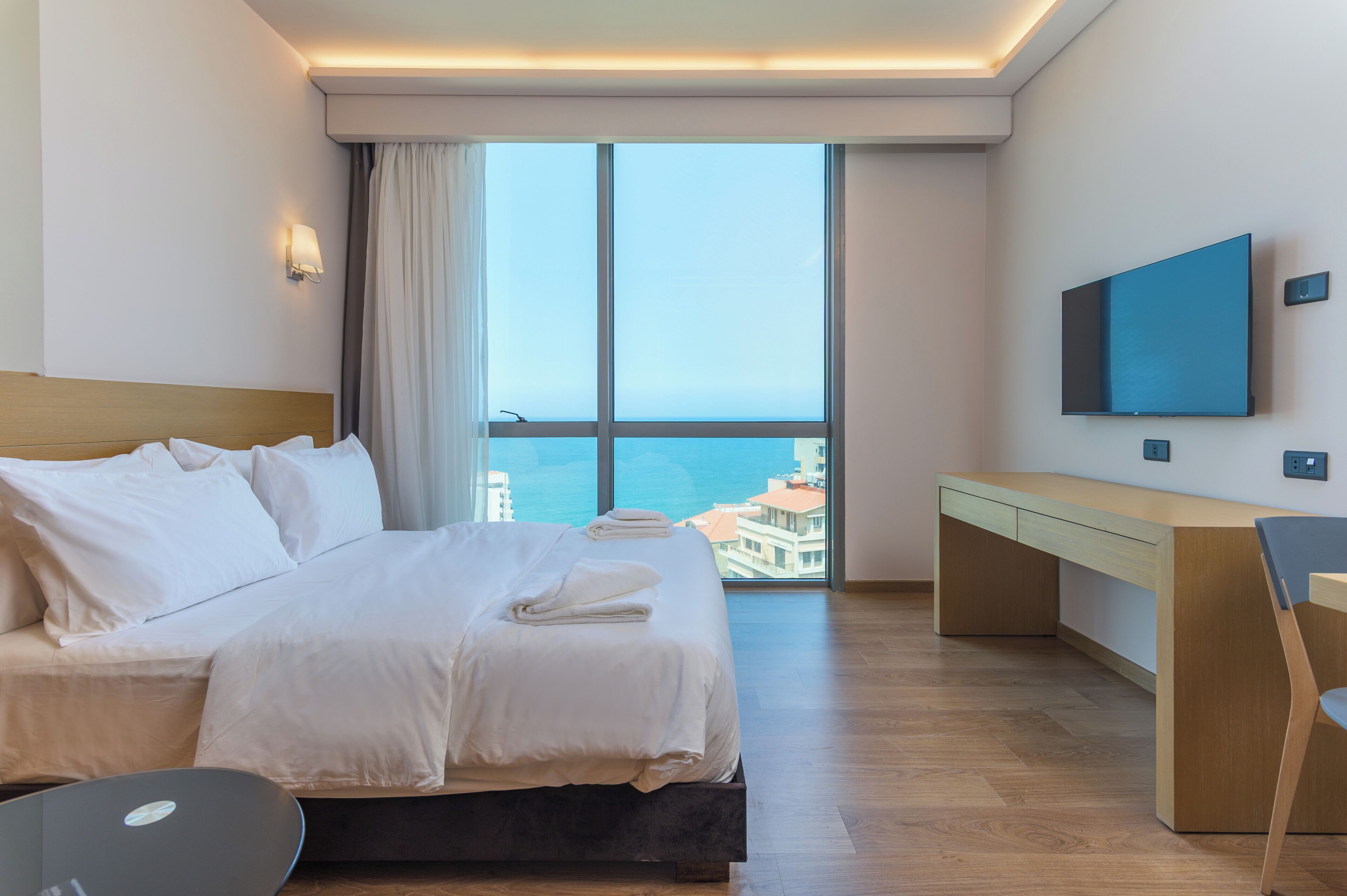 A modern hotel room with a large bed, a desk, and a TV.