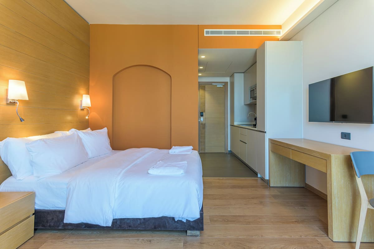 A modern hotel room with a bed, bedside lamps, a desk, and a TV.