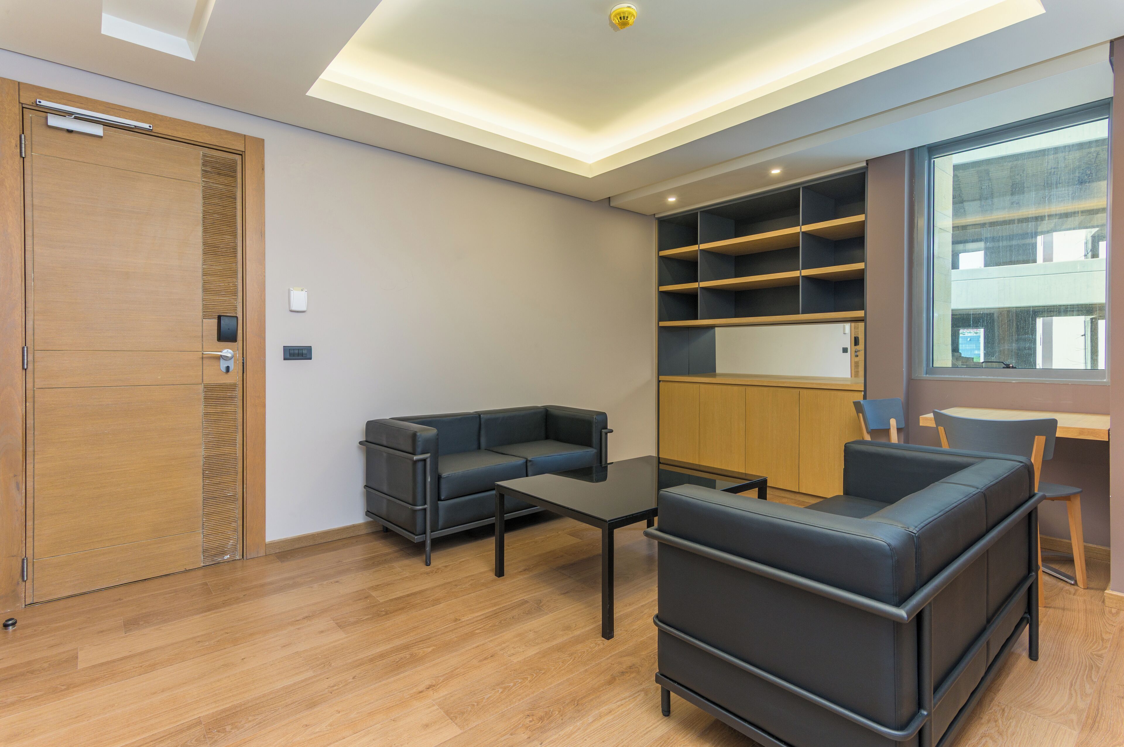 A modern living room with a sofa, a coffee table, and a built-in shelving unit.
