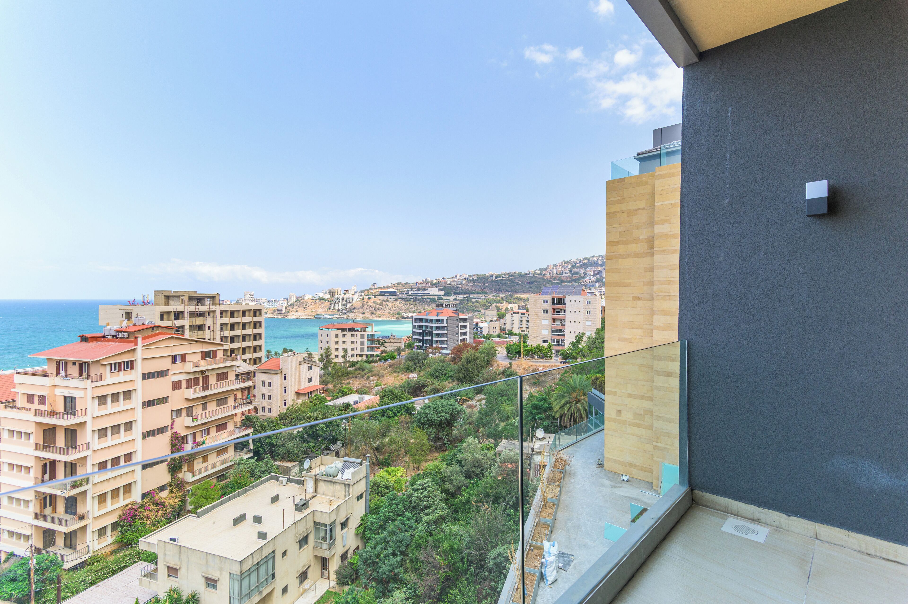 A balcony with a view of a coastal cityscape, including buildings and the sea.