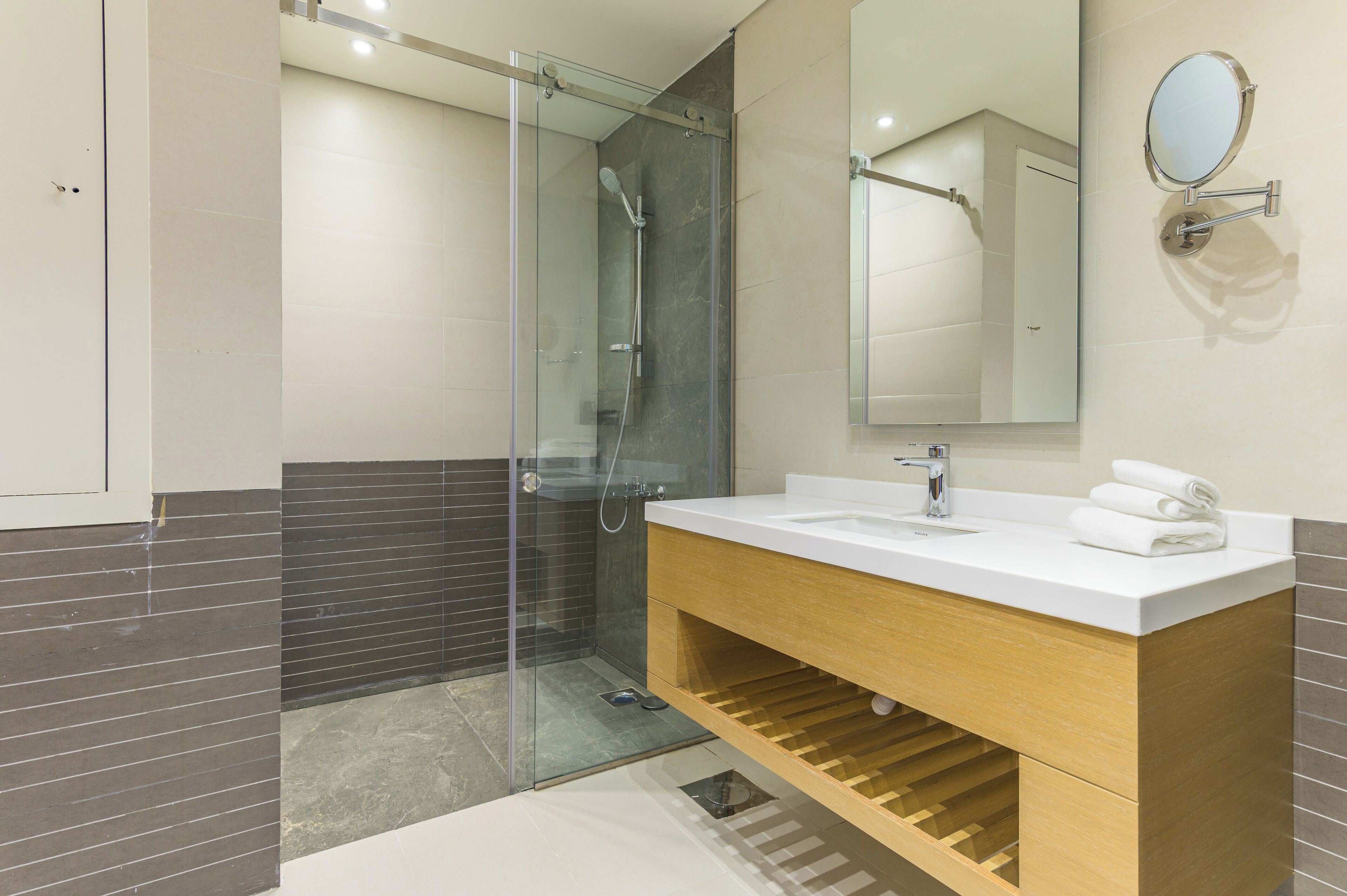 A modern bathroom with a glass-enclosed shower, a white sink, and a wooden vanity.