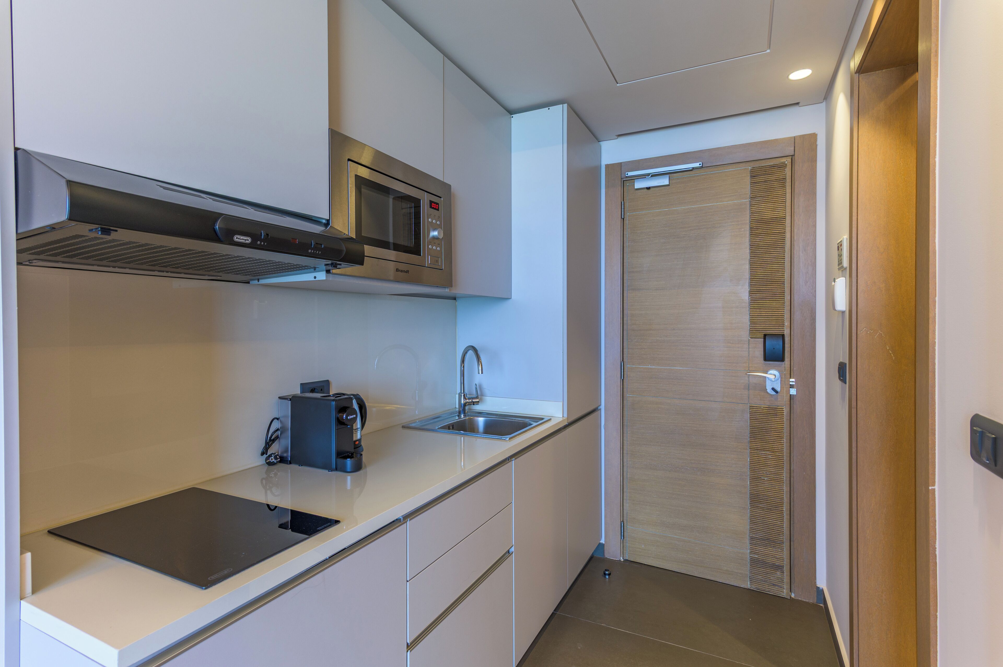 Una cocina moderna con microondas integrado, cafetera y un lavabo.