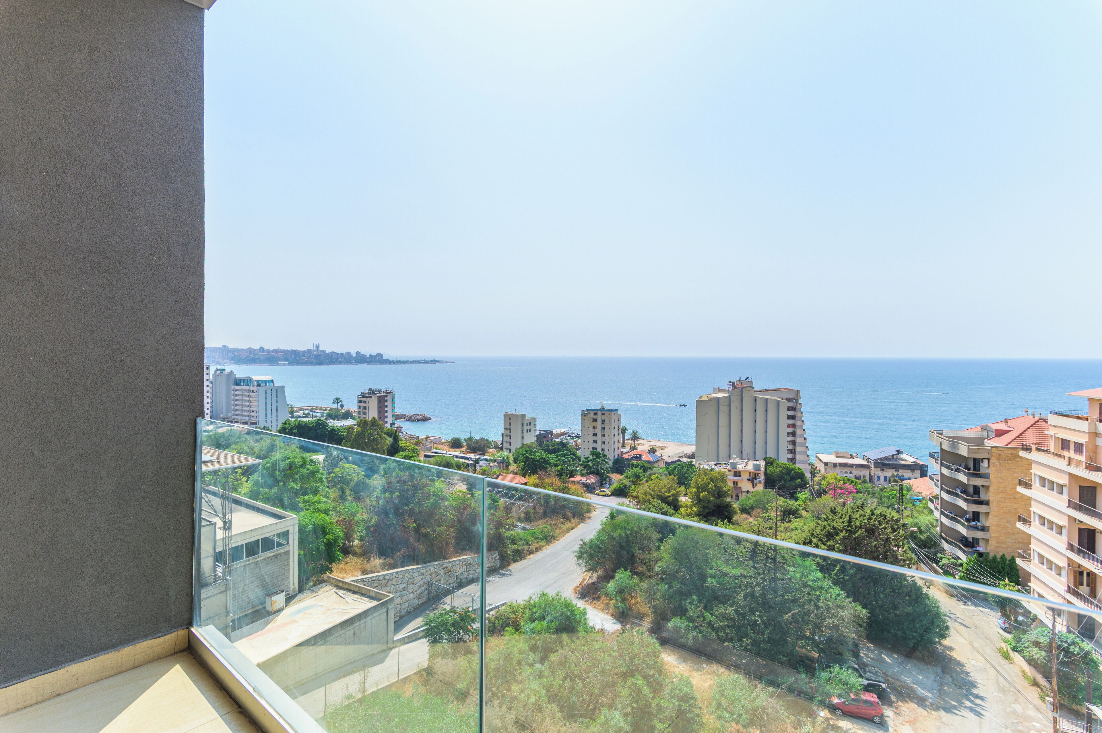 Un balcon offrant une vue dégagée sur le paysage urbain de la côte, avec ses bâtiments et la mer.