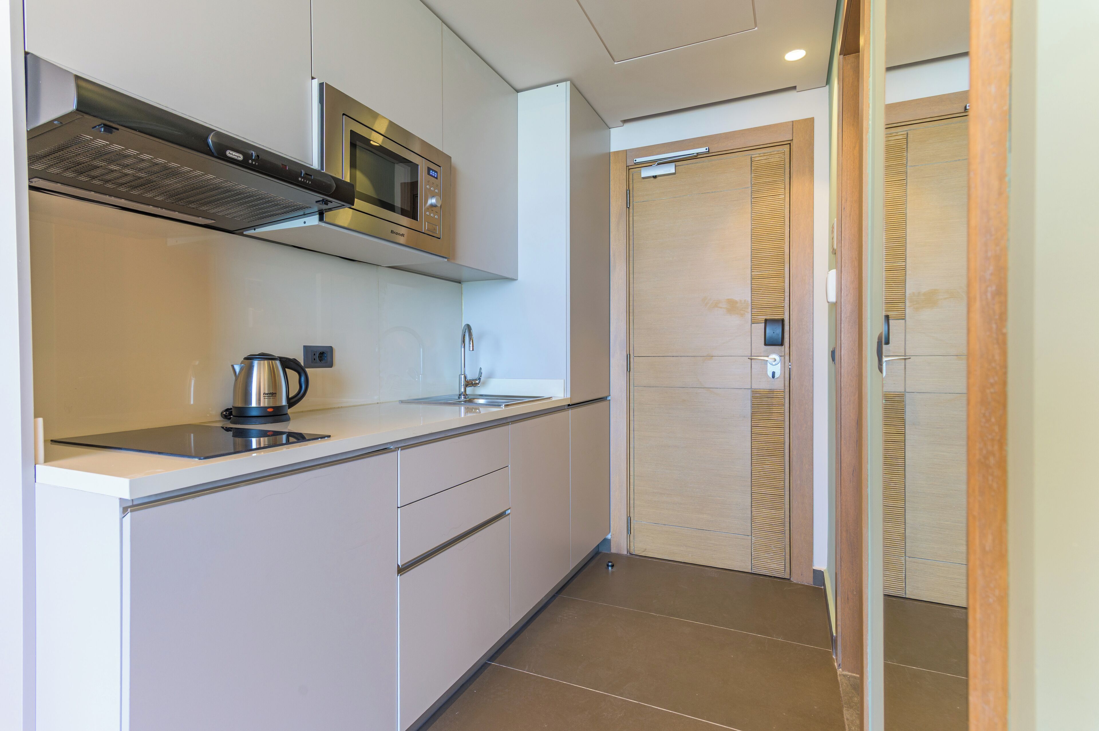 A modern kitchen with a microwave, kettle, and stainless steel sink.