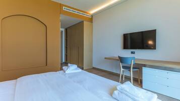 A hotel room with a bed, a desk, a chair, and a television.
