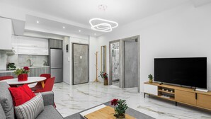 A modern living room with a grey sofa, a wooden coffee table, and a flat-screen TV on a wooden stand. - Eleanor by halu! (Thessaloniki)