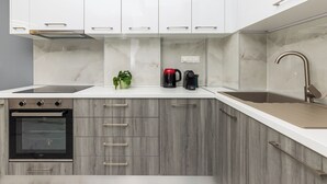 A modern kitchen with white cabinets, a built-in oven, a sink, and a coffee maker. - Eleanor by halu! (Thessaloniki)