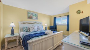 A bedroom with a bed, bedside tables, a desk with a TV, and a window with a view. - 5th Floor Perfect Location at The Summit w/Beach Chairs Included! (Panama City Beach)