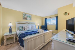 A bedroom with a bed, bedside tables, a desk with a TV, and a window with a view.