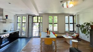 A modern kitchen with a dining area, large windows, and a ceiling light fixture. - Bright loft in the heart of Paris (Liège)