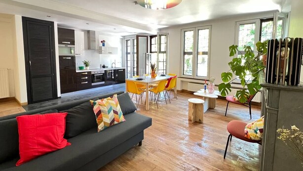 A modern living space with a kitchen, dining area, and a sofa with colorful cushions. - Bright loft in the heart of Paris (Liège)