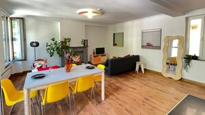 A modern living room with a dining area, wooden flooring, and a fireplace. - Bright loft in the heart of Paris (Liège)