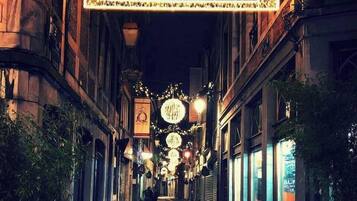 Een smalle straat met kinders hoofdverharding, verlichte borden en hangende lampen, wat wijst op een historische of toeristische omgeving.