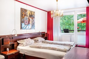 A hotel room with a bed, bedside tables, a lamp, a painting on the wall, a chandelier, and a window with curtains. - Apartment 'Rot-weiss' with Private Terrace and Wi-Fi (Bad Zwischenahn)